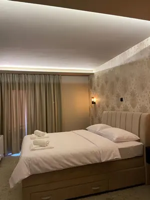 a bedroom with a large bed with white sheets at Apartmani Mila Mi in Kotor-Varoš