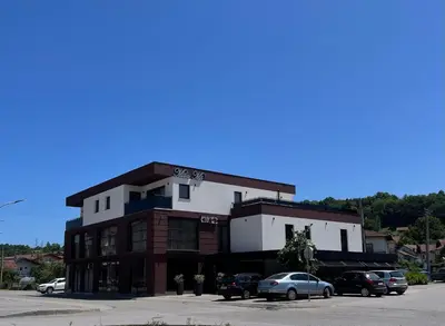 a building with cars parked in a parking lot at Apartmani Mila Mi in Kotor-Varoš
