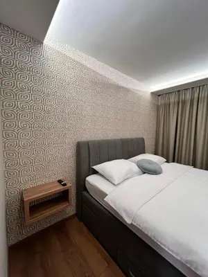 a bedroom with a bed with a night stand next to it at Apartmani Mila Mi in Kotor-Varoš