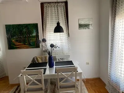 a dining room table with two chairs and a vase on it at Apolon I Apartment in Banja Luka