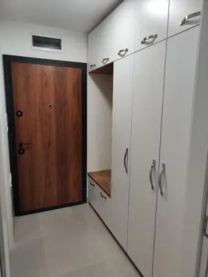 a closet with white cabinets and a wooden door at Apartman BULEVAR1 sa garažom in Doboj