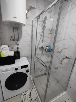 a bathroom with a shower and a washer and dryer at Apartman BULEVAR1 sa garažom in Doboj