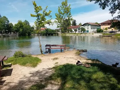 a picnic table on the shore of a lake at Apartman Orhideja in Bihać