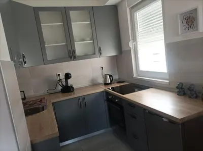 a kitchen with gray cabinets and a sink and a window at Apartman Ema in Banja Luka
