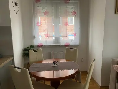 a dining room with a table and chairs and a window at Apartman Ema in Banja Luka