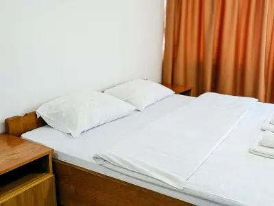 a bed with white sheets and pillows on it at Motel Dačo in Stara Bila