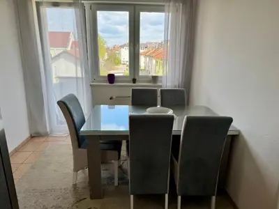 a dining room table with chairs and a window at Andjelka apartman in Modriča