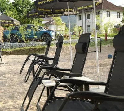 a row of lawn chairs with an umbrella at Apartmani SIMIĆ in Doboj