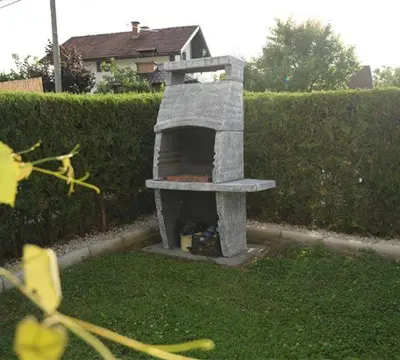 a stone oven sitting in the grass in a yard at Apartmani SIMIĆ in Doboj