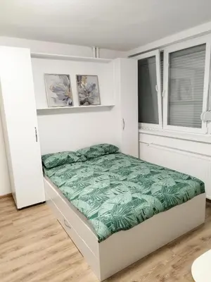 a bedroom with a bed with a green blanket at Boulevard Tuzla Studio Apartment in Tuzla