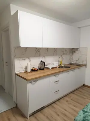 a kitchen with white cabinets and a wooden counter top at Boulevard Tuzla Studio Apartment in Tuzla