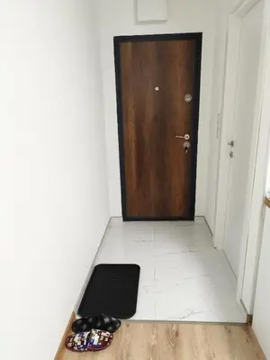 a hallway with a door and a pair of shoes at Boulevard Tuzla Studio Apartment in Tuzla