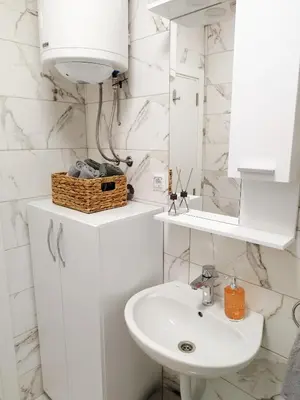 a white bathroom with a sink and a mirror at Boulevard Tuzla Studio Apartment in Tuzla