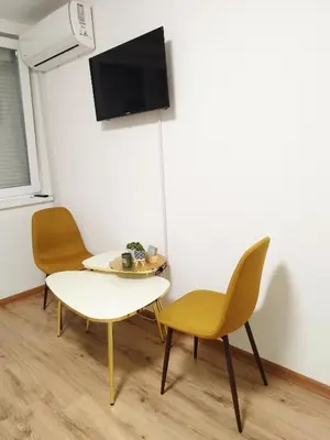a room with two chairs and a table and a tv at Boulevard Tuzla Studio Apartment in Tuzla