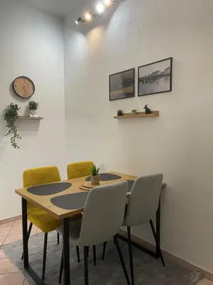 a dining room table with chairs and a clock on the wall at Apartman ROYAL in Sanski most