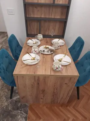 a wooden table with plates and glasses and blue chairs at URBAN apartment Banja Luka in Banja Luka