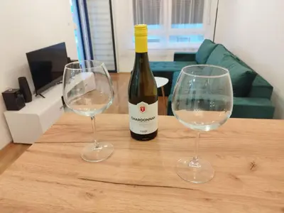a bottle of wine and two wine glasses on a table at Stan na dan Apartman Harmonija in Zalužani