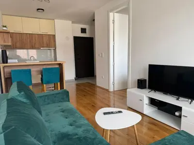 a living room with a green couch and a tv at Stan na dan Apartman Harmonija in Zalužani