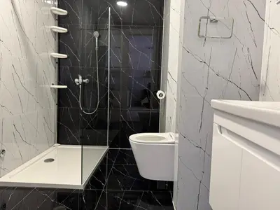 a black and white bathroom with a toilet and a shower at Stan na dan Apartman Harmonija in Zalužani