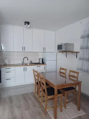 a kitchen with white cabinets and a wooden table and chairs at Hilandar in Teslić