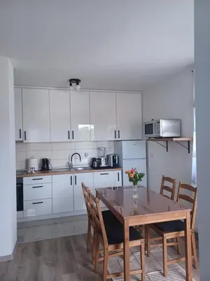 a kitchen with white cabinets and a wooden table with chairs at Hilandar in Teslić