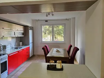 a kitchen with a wooden table and red cabinets at K&N centar Doboj in Doboj