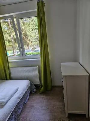 a bedroom with a bed and a window with green curtains at K&N centar Doboj in Doboj