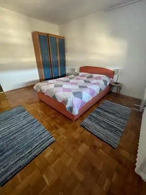 a bedroom with a bed and two rugs on the floor at Bambi Zenica in Zenica