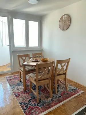 a dining room with a table and chairs on a rug at Bambi Zenica in Zenica