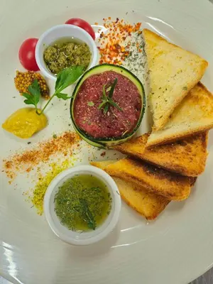 a white plate of food with toast and dips at Hotel Luna Bihać in Bihać