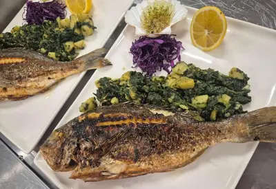 a plate of food with fish and vegetables on it at Hotel Luna Bihać in Bihać