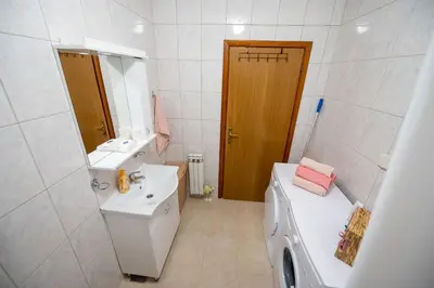 a white bathroom with a sink and a washing machine at Apartman Magija in Banja Luka