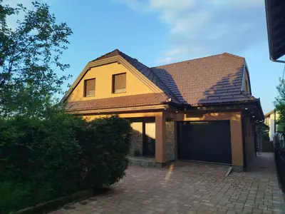 a yellow house with a garage on a brick driveway at Villa Orhan in Bihać