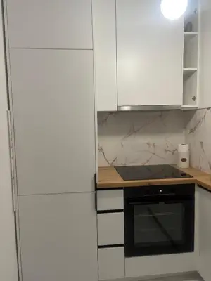 a kitchen with white cabinets and a black oven at Apartman ADA in Železnička Stanica Incel