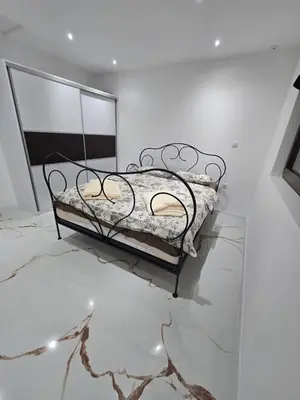 a black bed in a white room with a marble floor at Apartmani Mikić in Bosanski Šamac