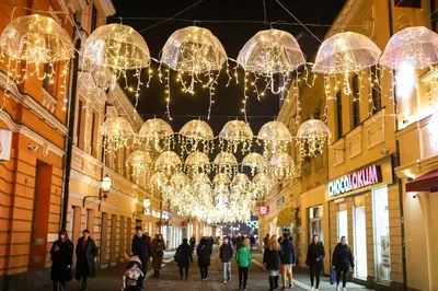 a group of people walking down a street with lights at Elena - stan na dan in Banja Luka