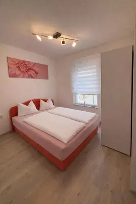 a bedroom with a bed with white sheets and a window at Apartman Sofija centar in Teslić