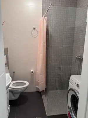 a bathroom with a toilet and a shower with a pink shower curtain at Apartman Sofija centar in Teslić