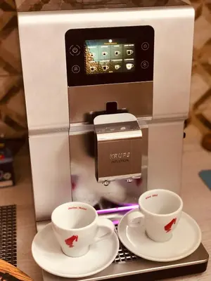 a coffee machine with two cups on plates at Apartman Sofija centar in Teslić