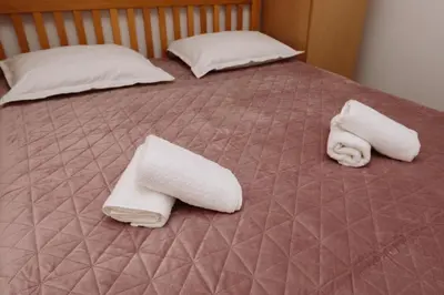 two beds with white towels and pillows on them at Apartman Eni in Livno