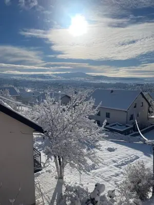 a tree covered in snow next to a building at Apartman Eni in Livno