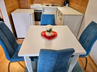 a white table with blue chairs and a candle on it at Apartman Dona in Bosanska Gradiška