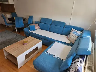 a living room with a blue couch and a table at Apartman Dona in Bosanska Gradiška