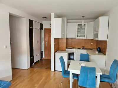 a kitchen and dining room with a table and blue chairs at Apartman Dona in Bosanska Gradiška