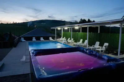 a large swimming pool with chairs and a patio at EJDE RESORT Šiljkovača in Velika Kladuša