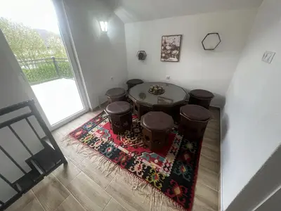 a room with a table and stools on a rug at Stone House Ripac in Bihać