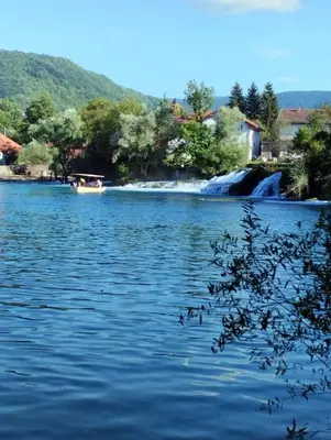 a boat on a river with a waterfall at Stone House Ripac in Bihać