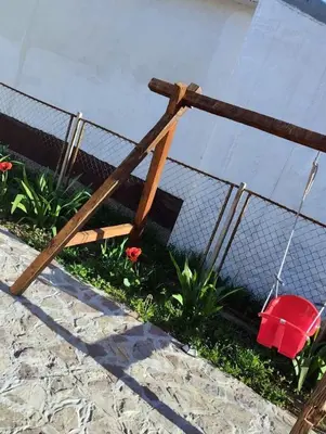 a wooden fence with a red chair in a garden at Stone House Ripac in Bihać