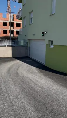 a parking lot next to a building with a garage at Stan na dan Gradiška in Bosanska Gradiška