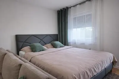 a bedroom with a large bed with a window at Muki Oaza Apartman in Tuzla